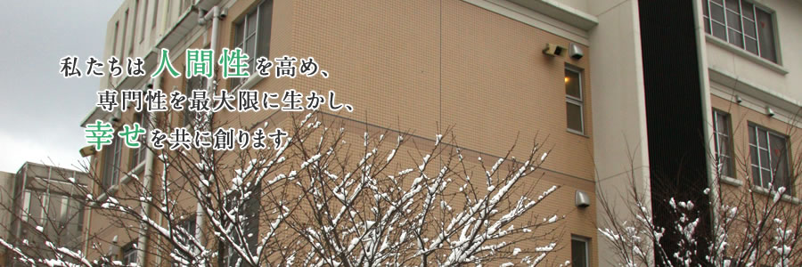 病院の外観と雪が積もった木の枝「私たちは人間性を高め、専門性を最大限に生かし、幸せを共に創ります」