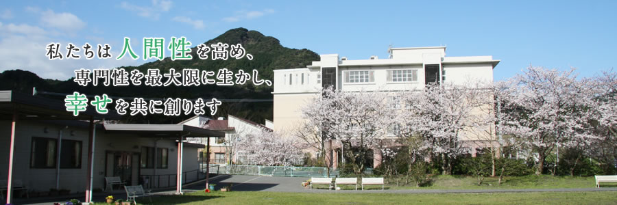 満開の桜の木と病院の外観「私たちは人間性を高め、専門性を最大限に生かし、幸せを共に創ります」